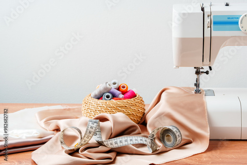 A sewing machine on a wooden table with fabric and thread organized in a basket