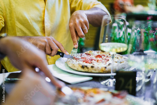 Person eating pizza outdoors - Italian food lifestyle and dining experience with wine and friends photo