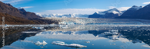 Panorama of the Moon Glacier, Scoresby Sund, Eastern Greenland. Mirror reflection of the mountains, tundra and glacial ice with icebergs in the blue fjord waters. photo