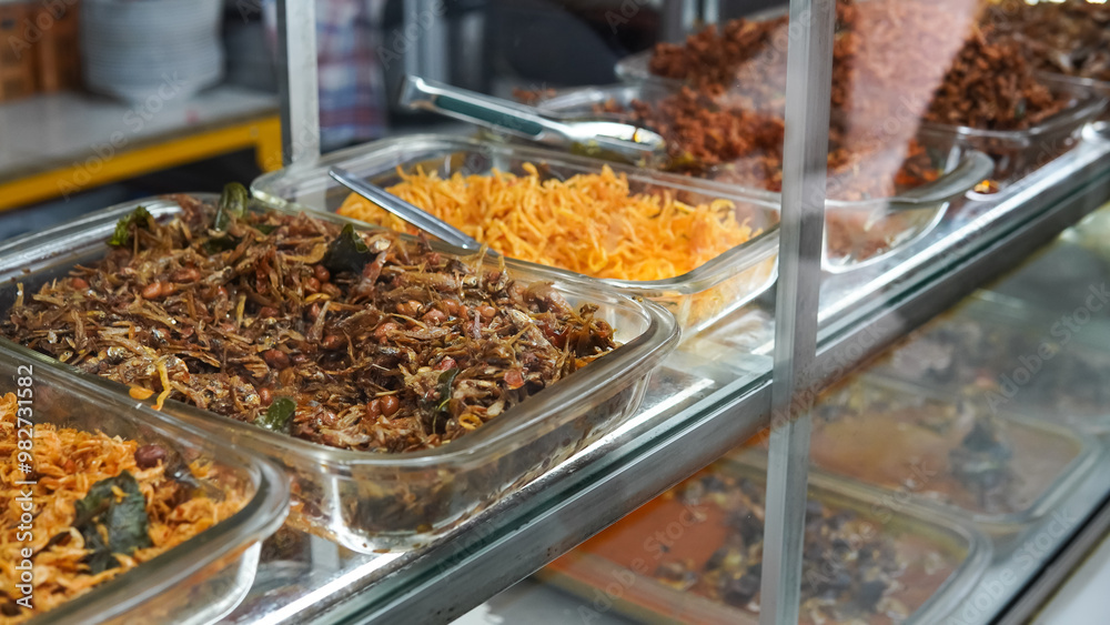 Fototapeta premium Food stalls called warteg share a variety of buffet traditional menus of indonesia with vegetables, chicken curry sauce, beef, eggs, tofu, tempeh. Menu in glass display case. 