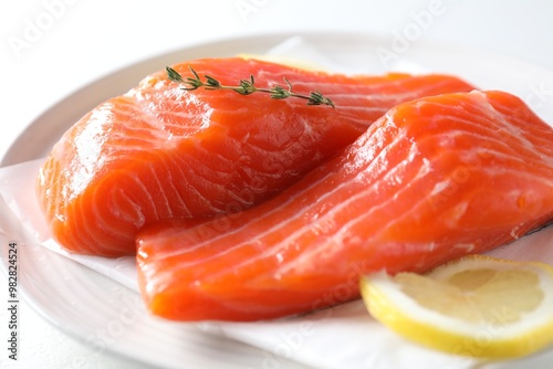 Pieces of fresh salmon with thyme and lemon on white table, closeup