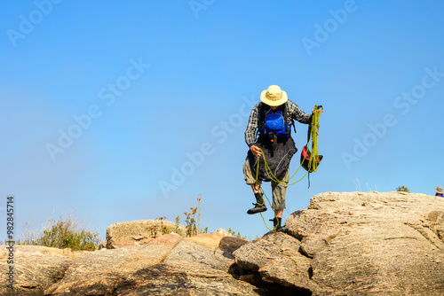 Photography Sea kayaker wearing a pfd and spray skirt stands on rock shore handling a safety