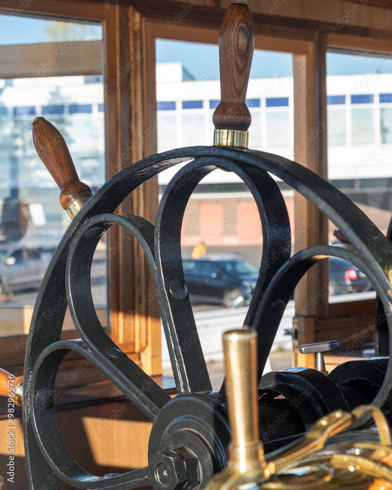 antique cast-iron steering wheel with wooden handles in the captain's cabin of the steamer. natural light. antique cast-iron steering wheel with wooden handles in the captain's cabin of the steamer. natural light.