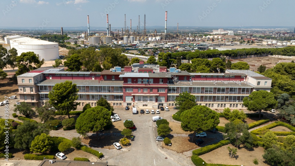 Fototapeta premium Aerial view of Testa Hospital in Taranto, Puglia, Italy. In background is Taranto Steelworks, also known as ILVA plant.