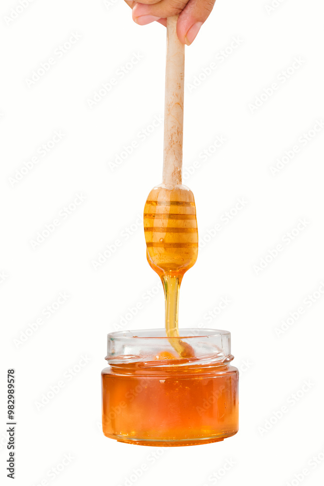 Honey glass jar and wooden spoon isolated on white background as package design element Honey glass jar and wooden spoon isolated on white background as package design element