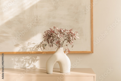 A stylish modern vase with decorative branches on a sideboard  in a modern living room.