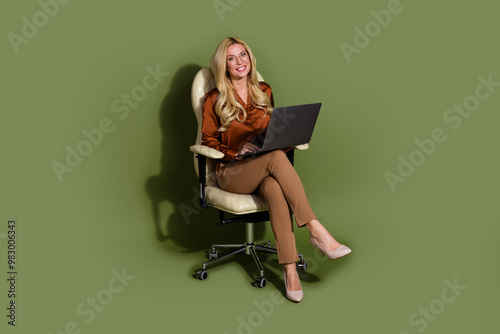 Photo of charming lovely lady wear trendy clothes sit office armchair hold netbook isolated on khaki color background