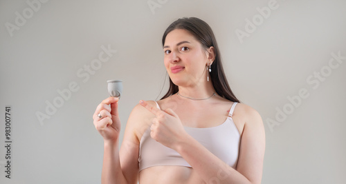 Woman holds a tampon and menstrual cup, highlighting psychological health and products supporting emotional well-being during menstruation.