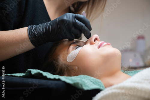 Beauty Close-up of a young woman having her eyelashes lash lifting enhanced with an eyelash lift by a beautician in a beauty salon. Shaping eye lash correction, color, curler, glue balm and mascara.