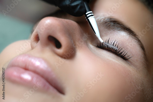 Beauty Close-up of a young woman having her eyelashes lash lifting enhanced with an eye lash lift by a beautician in a beauty salon. Shaping eyelash correction, color, curler, glue balm and mascara.