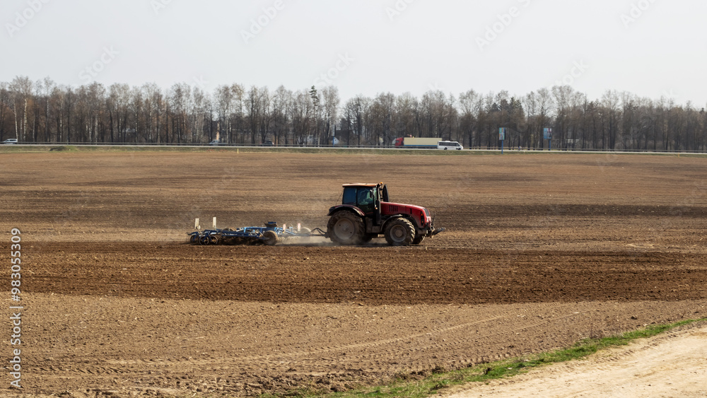 Obraz premium Red tractor is plowing a field closeup