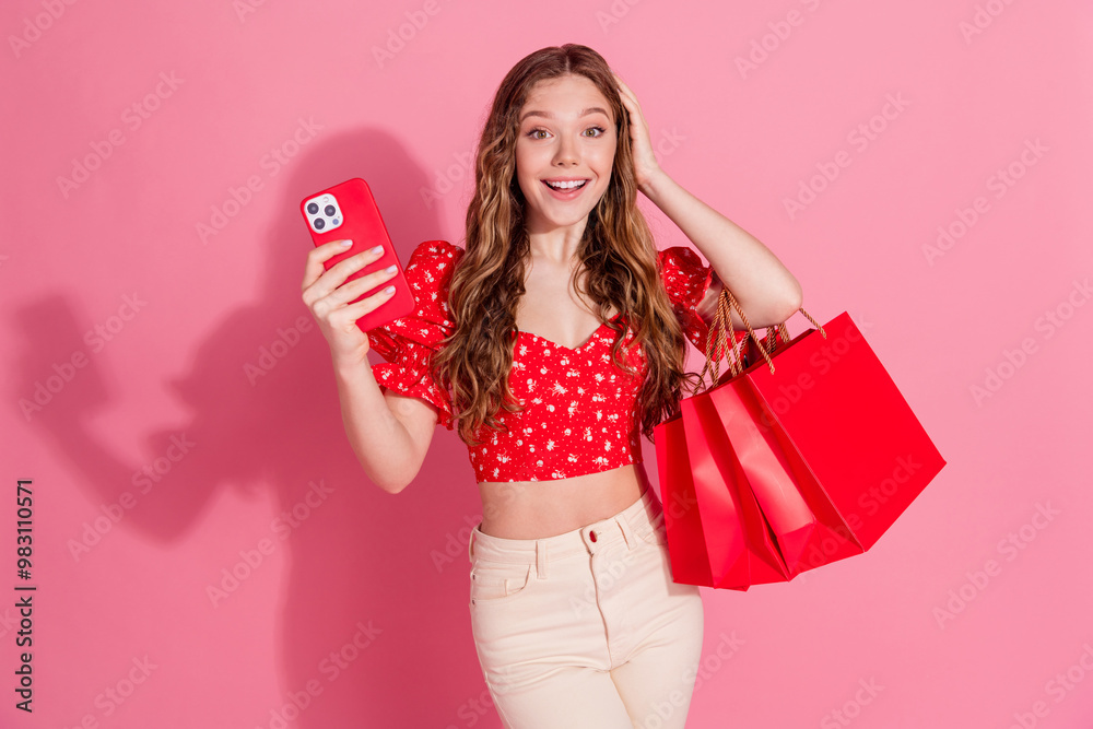 Fototapeta premium Photo portrait of attractive teen woman hold gadget excited shopping bags dressed stylish red clothes isolated on pink color background