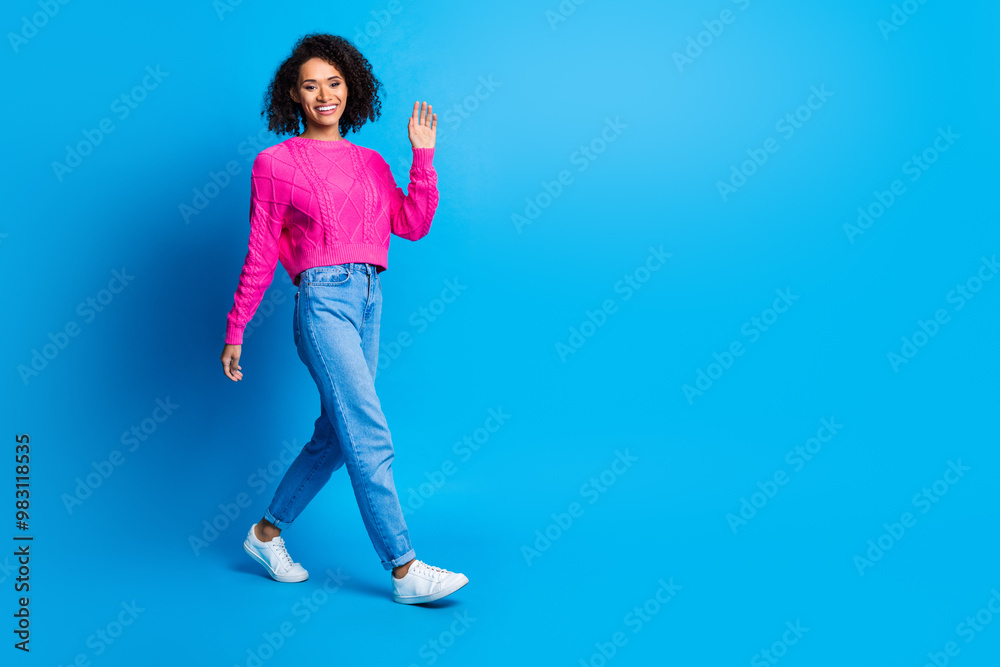 Full length photo of lovely young lady walk wave hand dressed stylish pink garment isolated on blue color background Full length photo of lovely young lady walk wave hand dressed stylish pink garment isolated on blue color background