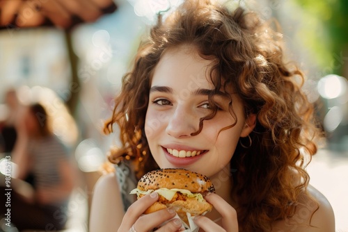 A woman with curly hair is eating a hamburger, generative ai image