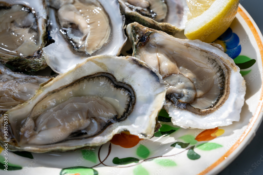 Plate with fresh live oysters with citron, bread, butter and white wine served at restaurant in oyster-farming village, Arcachon bay, Gujan-Mestras port, France Plate with fresh live oysters with citron, bread, butter and white wine served at restaurant in oyster-farming village, Arcachon bay, Gujan-Mestras port, France