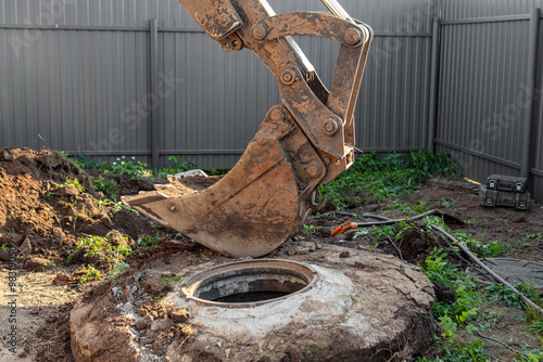 Dismantling of the well with an excavator. Old concrete well cover. Replacing the well