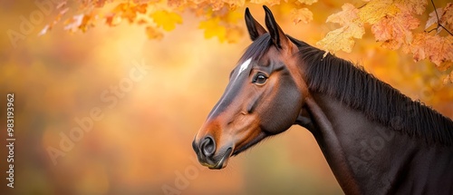  A brown horse faces a tree, its head adorned with yellow leaves, turned to one side photo