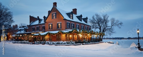 A historic brick inn located on a snowy waterfront, its facade adorned with festive lights and greenery, offering warm, welcoming lodgings for winter travelers