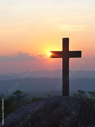 Crucifix silhouetted against a vibrant sunset over mountainous landscape