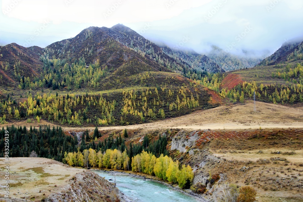 Naklejka premium A serene landscape featuring mountains, a river, and autumn foliage.