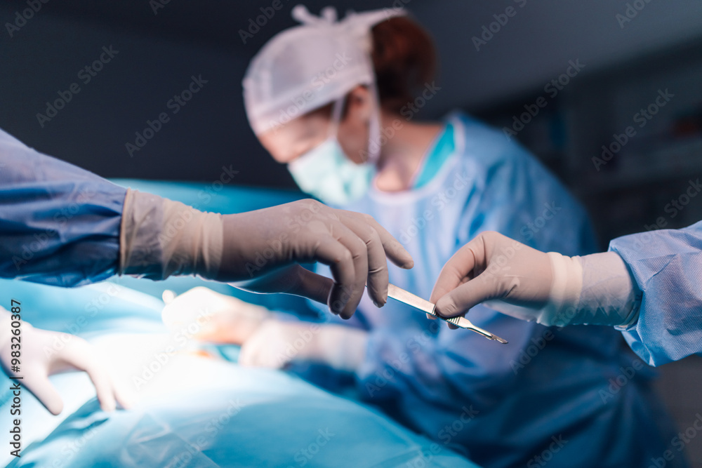 Hands passing scalpel in operating room with focused surgical team. Hands passing scalpel in operating room with focused surgical team.