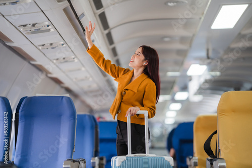 Ready for Takeoff: A young woman stows her luggage in the overhead compartment, her face alight with anticipation for the journey ahead.  photo