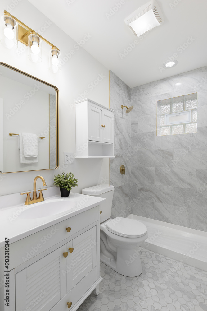 A white bathroom with gold lights, faucet, and light and a shower with marble tiles. A white bathroom with gold lights, faucet, and light and a shower with marble tiles.