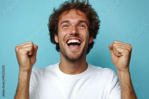 A Happy Man With Curly Hair and a White T-Shirt Raises His Fists in Celebration