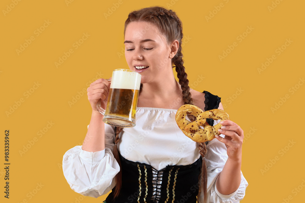 Young woman in traditional German clothes with beer and pretzel on yellow background Young woman in traditional German clothes with beer and pretzel on yellow background