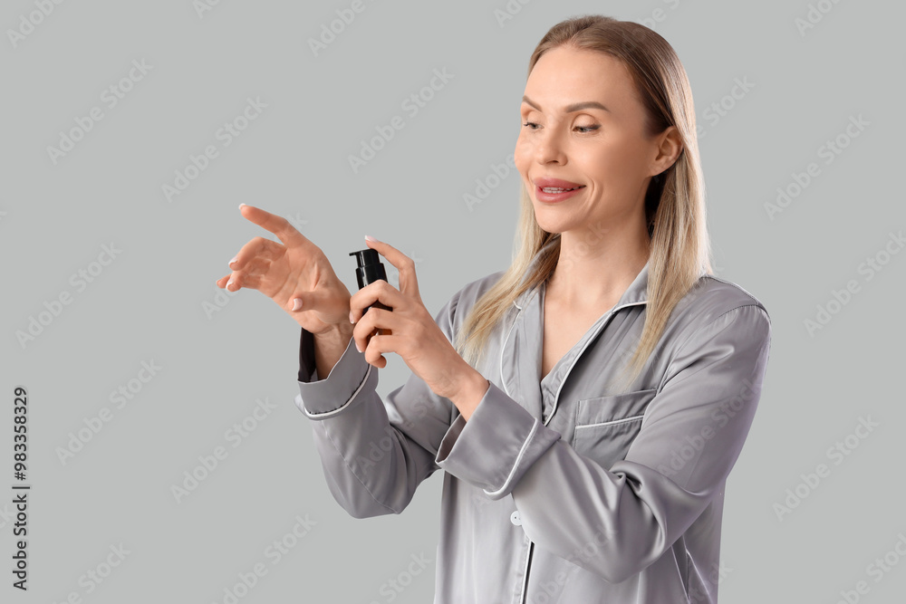Beautiful woman in pajamas applying cosmetic product on light background Beautiful woman in pajamas applying cosmetic product on light background