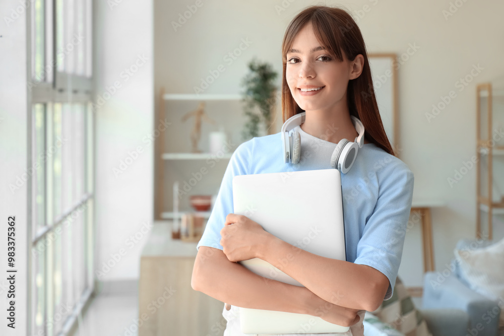 Happy female student with headphones and laptop near window at home Happy female student with headphones and laptop near window at home