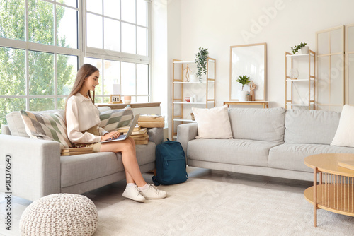 Happy female student with backpack, books and laptop studying at home