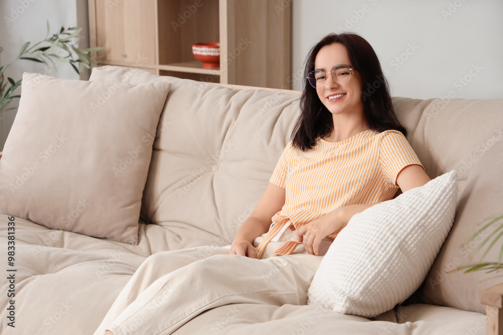 Young woman sitting on beige sofa at home Young woman sitting on beige sofa at home