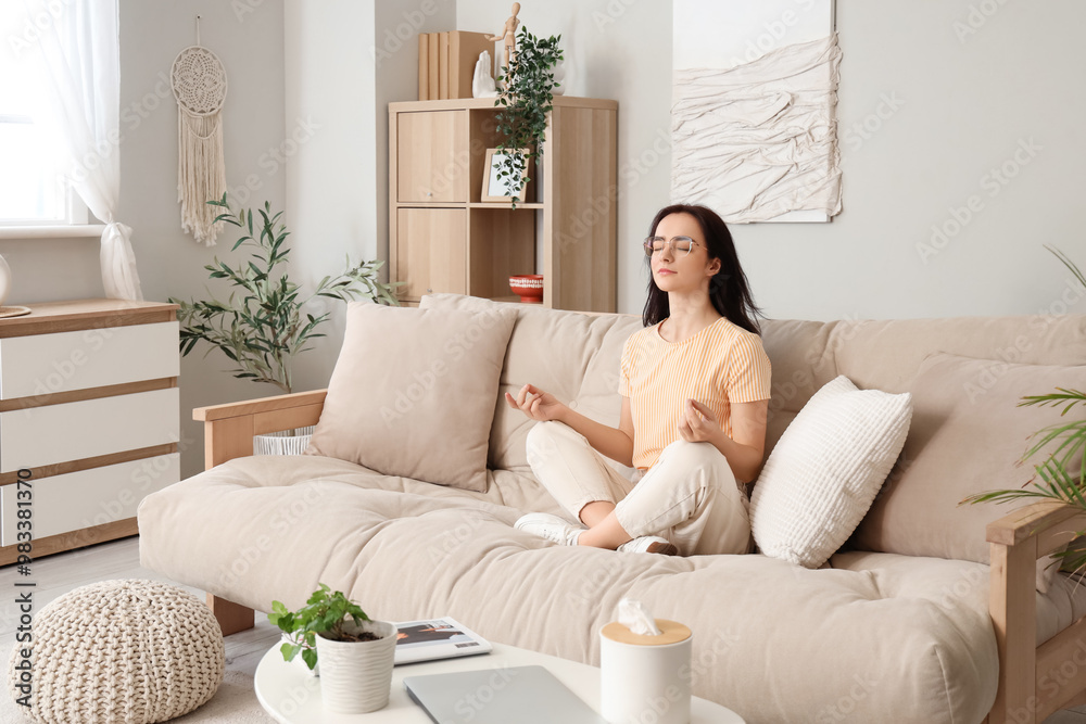 Young woman sitting on beige sofa at home Young woman sitting on beige sofa at home