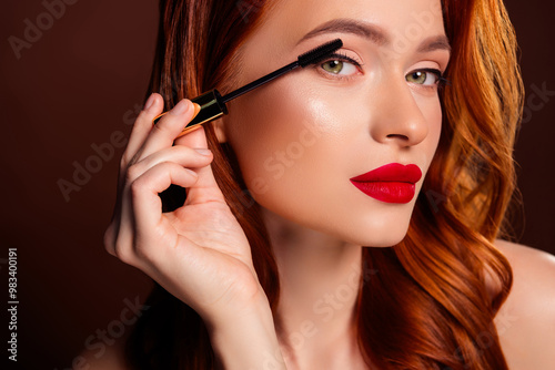 Close up photo of gorgeous attractive lady applying mascara make up isolated on brown color background
