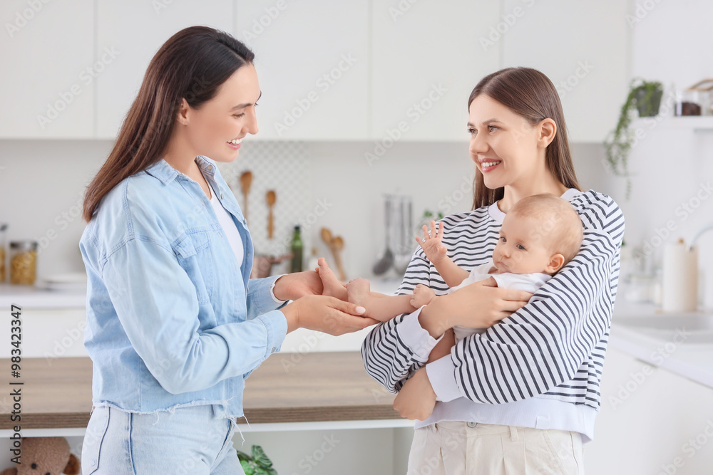 Young lesbian couple with their little baby in kitchen Young lesbian couple with their little baby in kitchen
