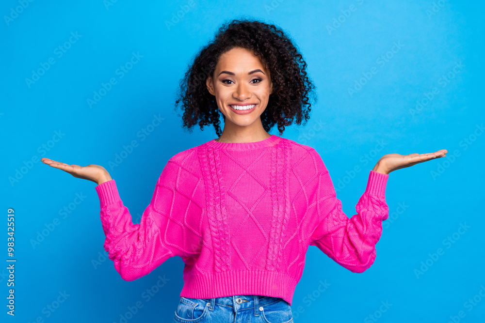 Portrait of pretty young lady hold empty space vs wear pink pullover isolated on blue color background Portrait of pretty young lady hold empty space vs wear pink pullover isolated on blue color background