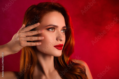 Photo of attractive gorgeous woman look empty space touch face lifting shoulders off isolated on red color background photo