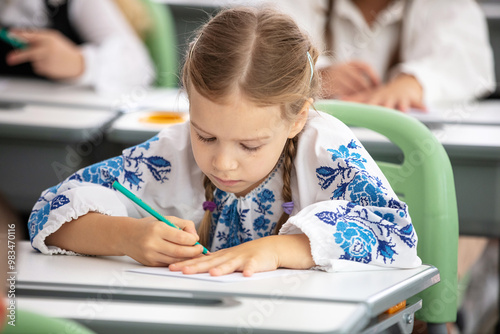Wallpaper Mural Cute young girl sitting at desk at school and holding pencil Torontodigital.ca