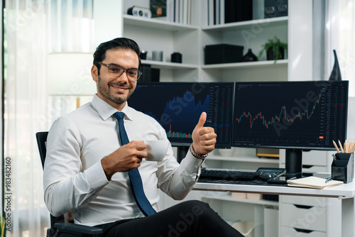 Profile of successful in trader businessman looking at camera with two stock exchange investment screens with raising fist up and thumb up in dynamic financial technology graph stock market. Surmise.