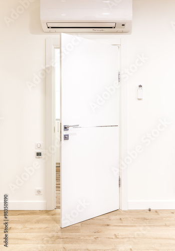 White opened door in modern home with air conditioner and wooden floor