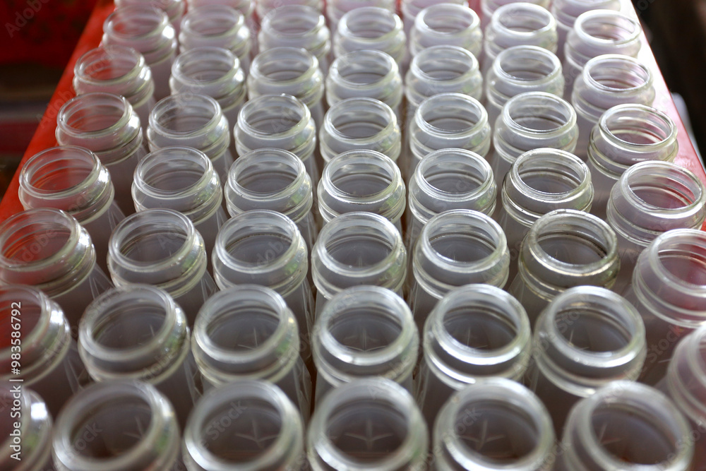 Top view of many glass bottles with their caps open and lined up. Top view of many glass bottles with their caps open and lined up.