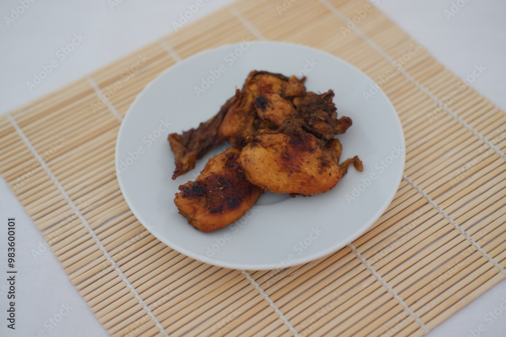 Fried chicken on a white plate with a bamboo mat Fried chicken on a white plate with a bamboo mat