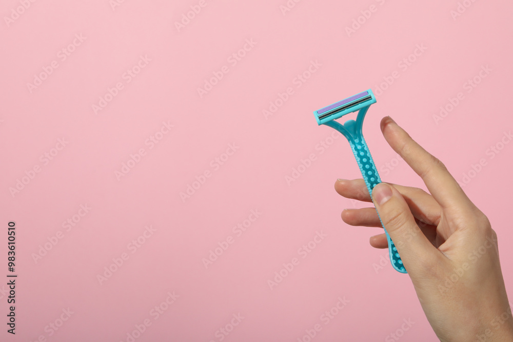 Shaving razor in hand on pink background Shaving razor in hand on pink background
