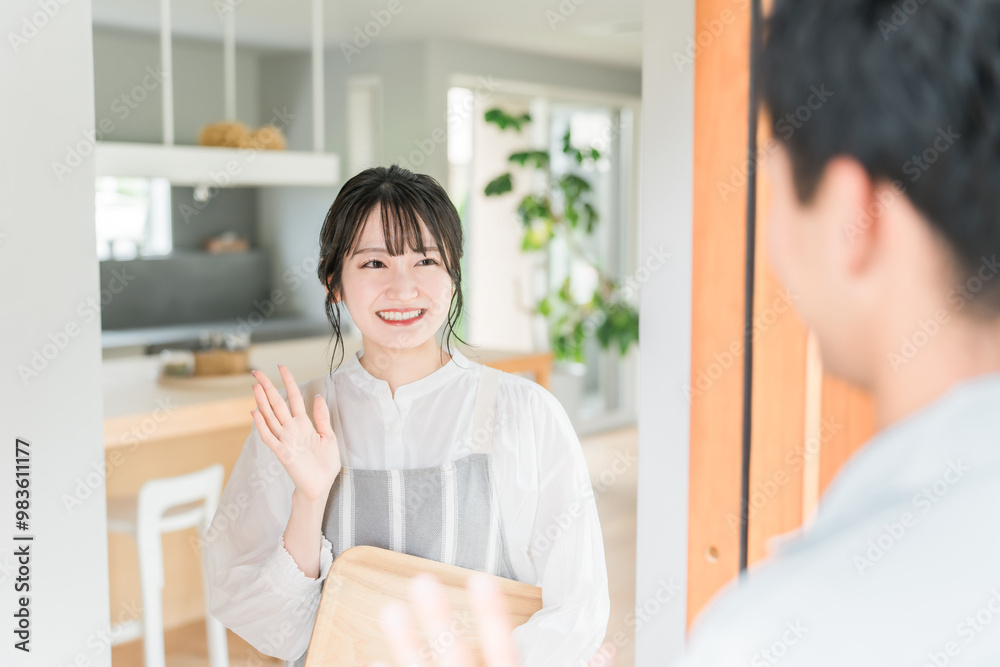 Obraz premium 朝出勤する夫・旦那を笑顔で見送りする若いアジア人女性・妻 