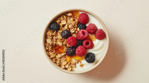 a bowl of fresh granola with greek yogurt topped with honey and fresh berries against an isolated light beige background