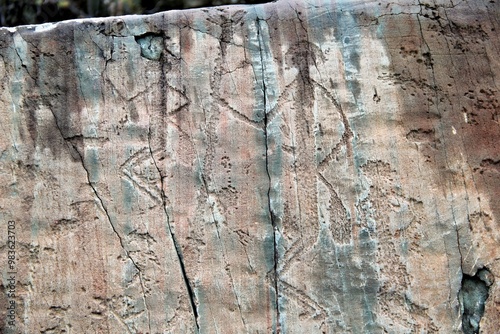 Ancient petroglyphs depicting human figures on a rock surface. photo