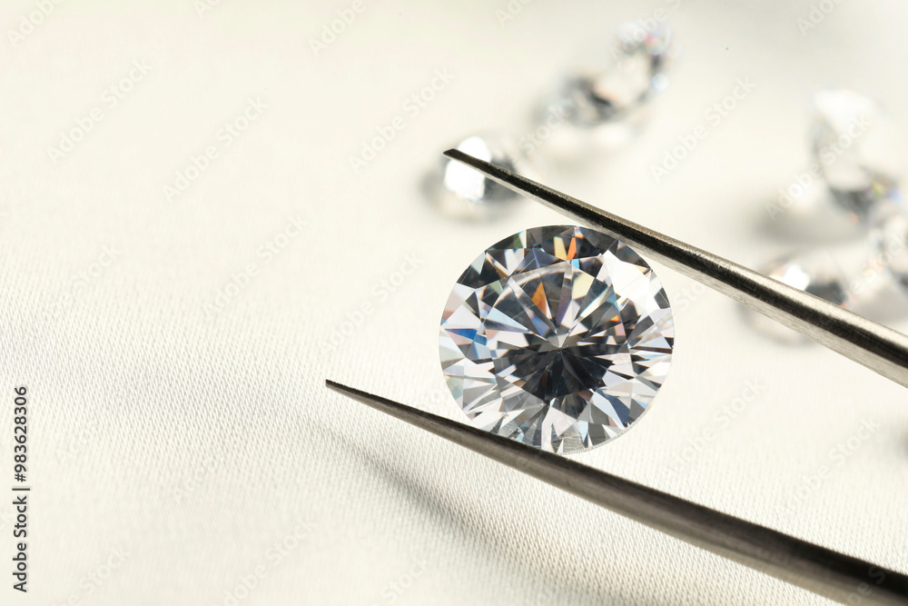 Tweezers with beautiful shiny diamonds on white fabric, closeup. Space for text Tweezers with beautiful shiny diamonds on white fabric, closeup. Space for text