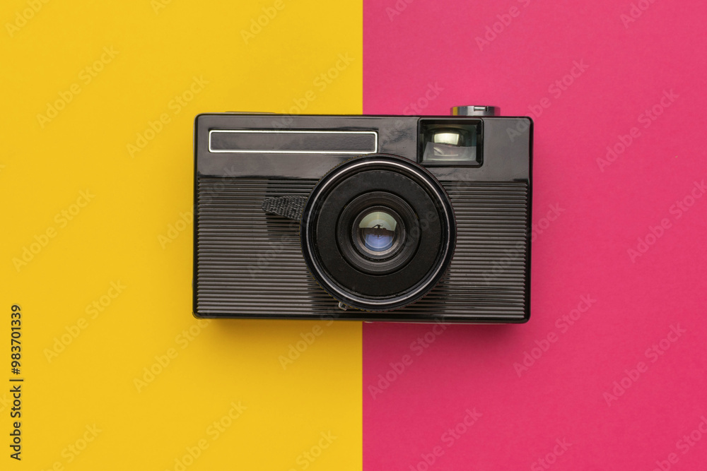 Fototapeta premium Vintage Film Camera on Vibrant Split Yellow and Pink Background