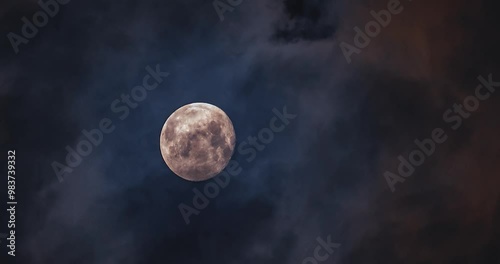 The moon is moving up, shining through the clouds.